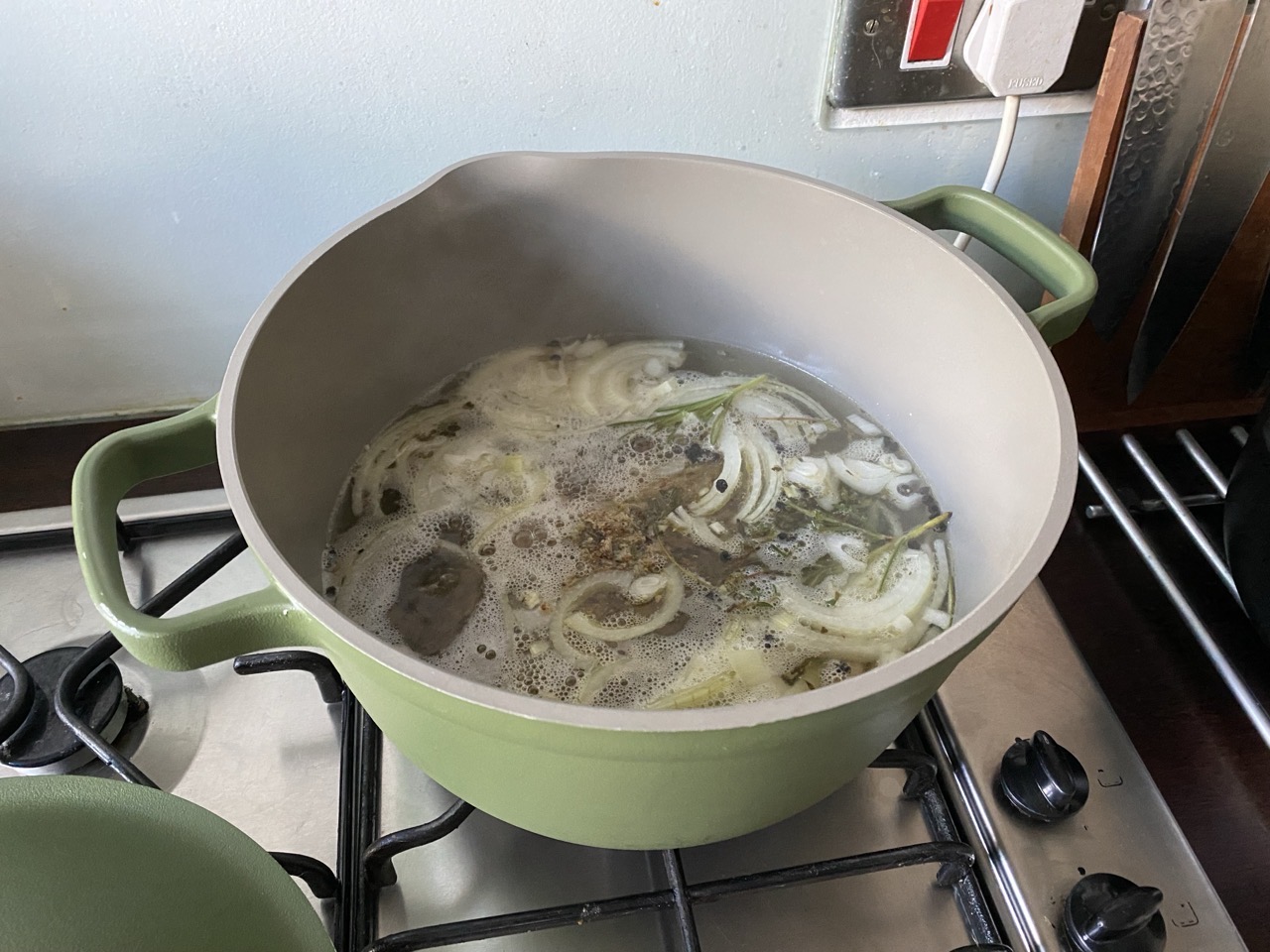 Some lamb stock in a pot! There are onions and lamb and pepper and salt and rosemary and thyme