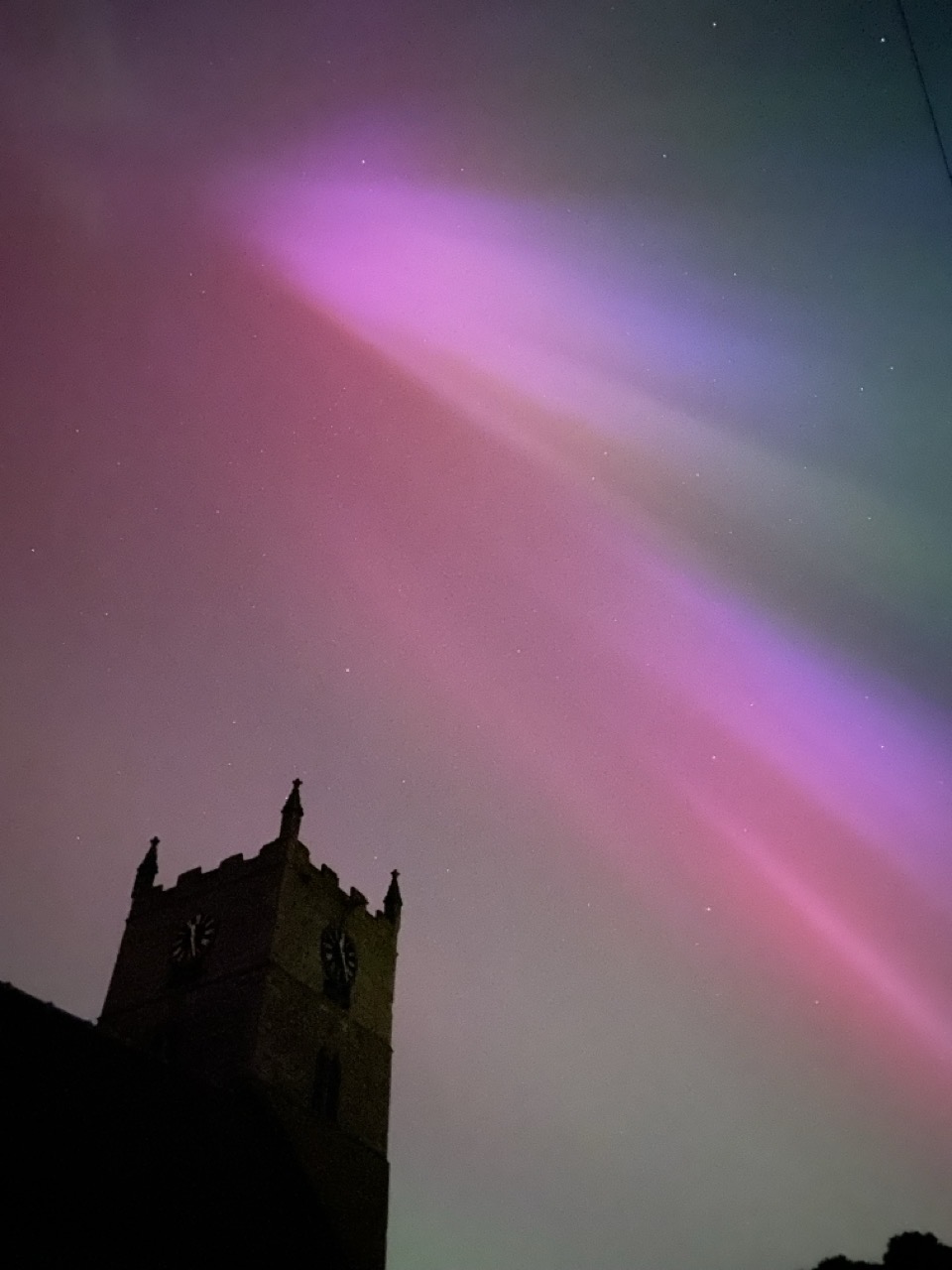 Northern lights with the silhouette of a church spire