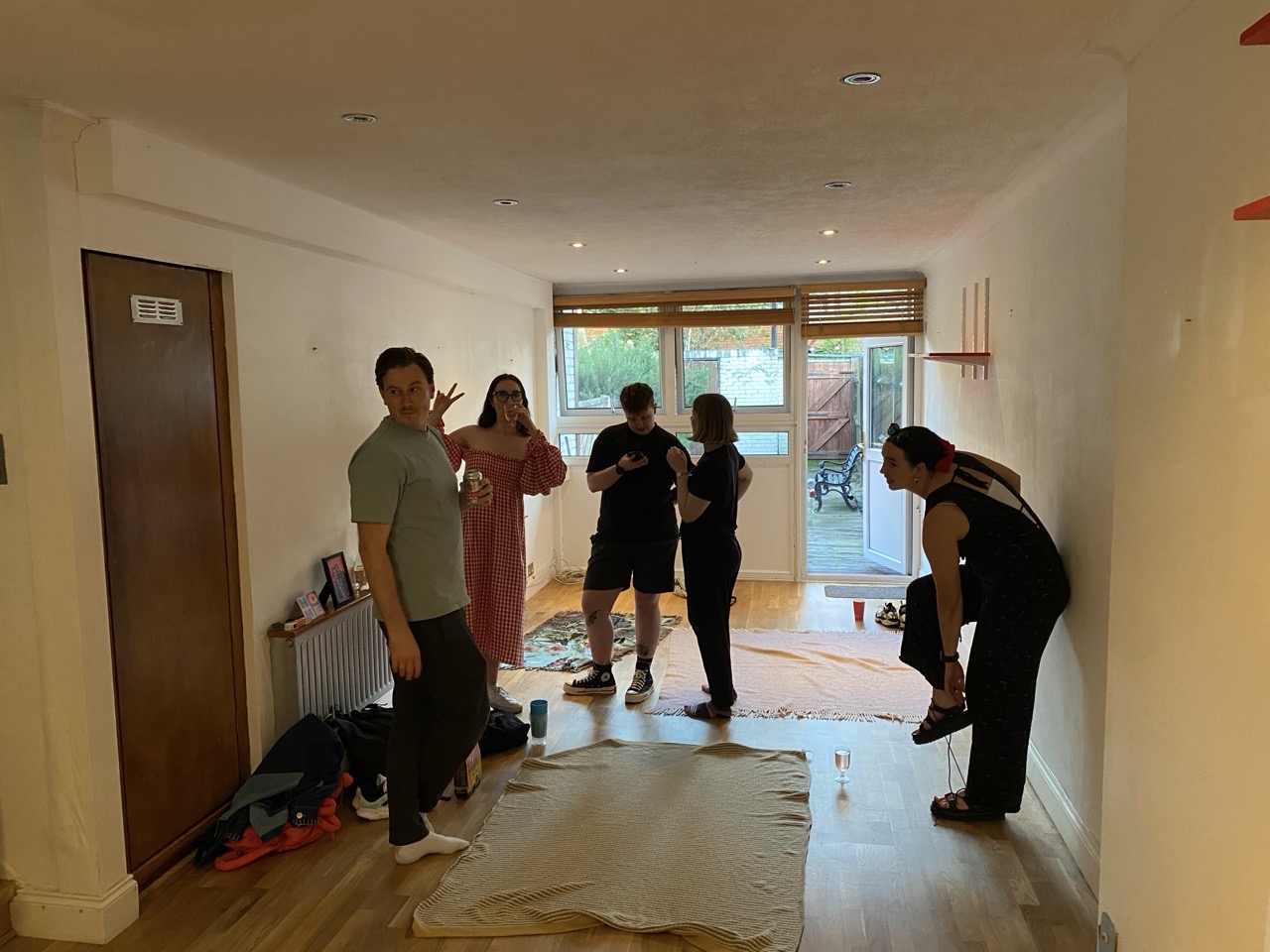 Some of our pals milling about with drinks. There are picnic rugs on the floor.