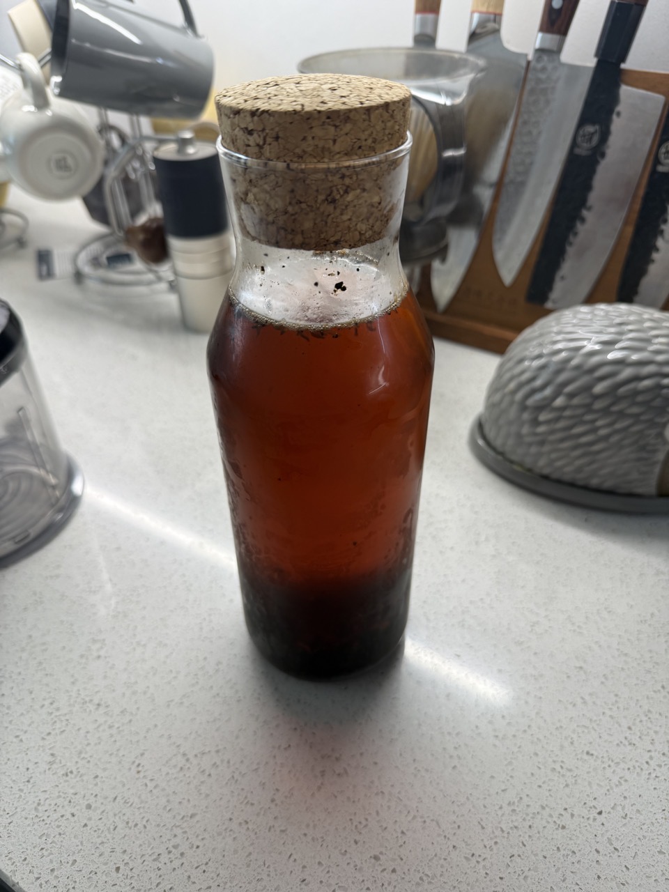 A glass bottle full of coffee with a cork in the top